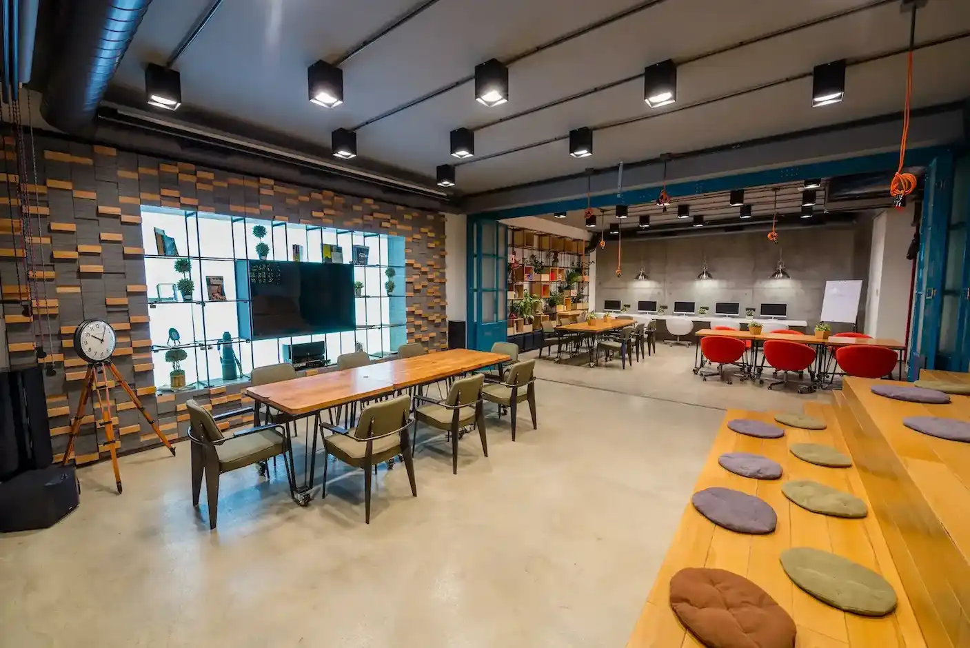 Cafetería de diseño industrial con pared de ladrillo visto, barra rústica de madera y hormigón, máquina de café profesional, estanterías abiertas y una cálida iluminación vintage con bombillas Edison colgantes, creando un ambiente acogedor.